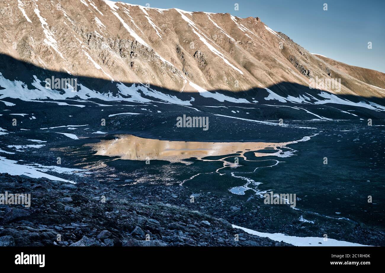 Schöne Landschaft des Bergsees mit Eis und Reflexion der verschneiten Berge bei Sonnenaufgang Stockfoto