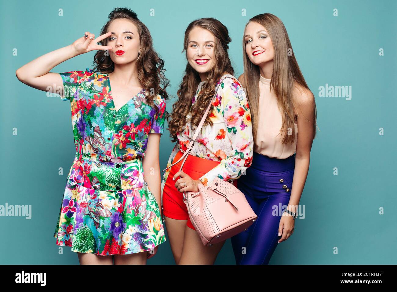 Schöne modische Mädchen in helle Kleidung bei Kamera vor azurblauem Hintergrund lächelnd. Stockfoto