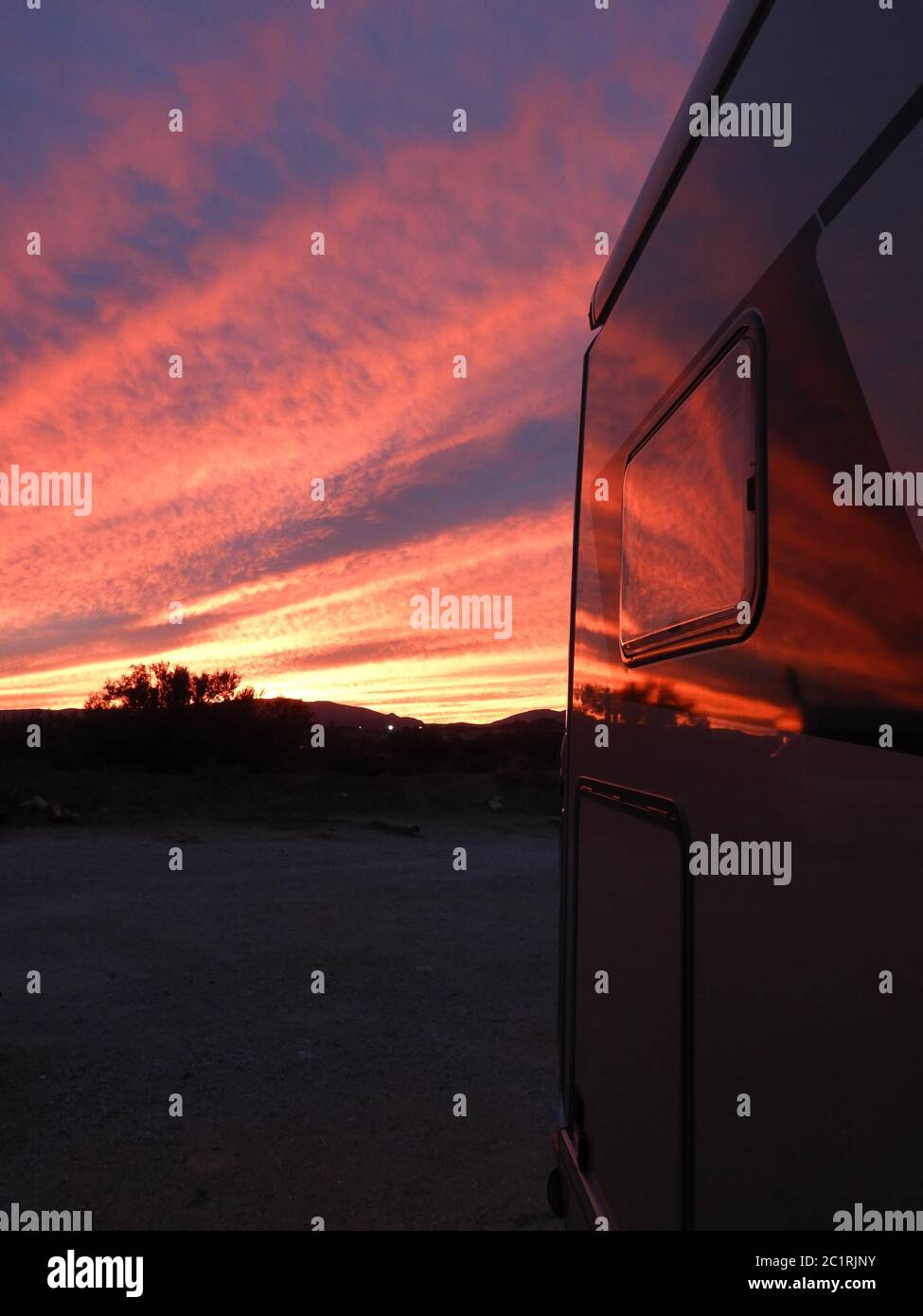 Farbenfrohe rote und orangefarbene Sonnenuntergänge, die sich in einem Wohnmobil widerspiegeln Stockfoto