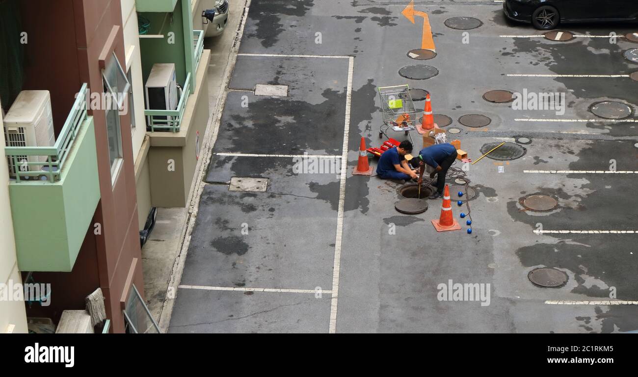 Bangkok, Thailand - 16. Juni 2020: Zwei Arbeiter arbeiten am Schachtloch, um unterirdische Kanalisation auf Wartung zu überprüfen Stockfoto