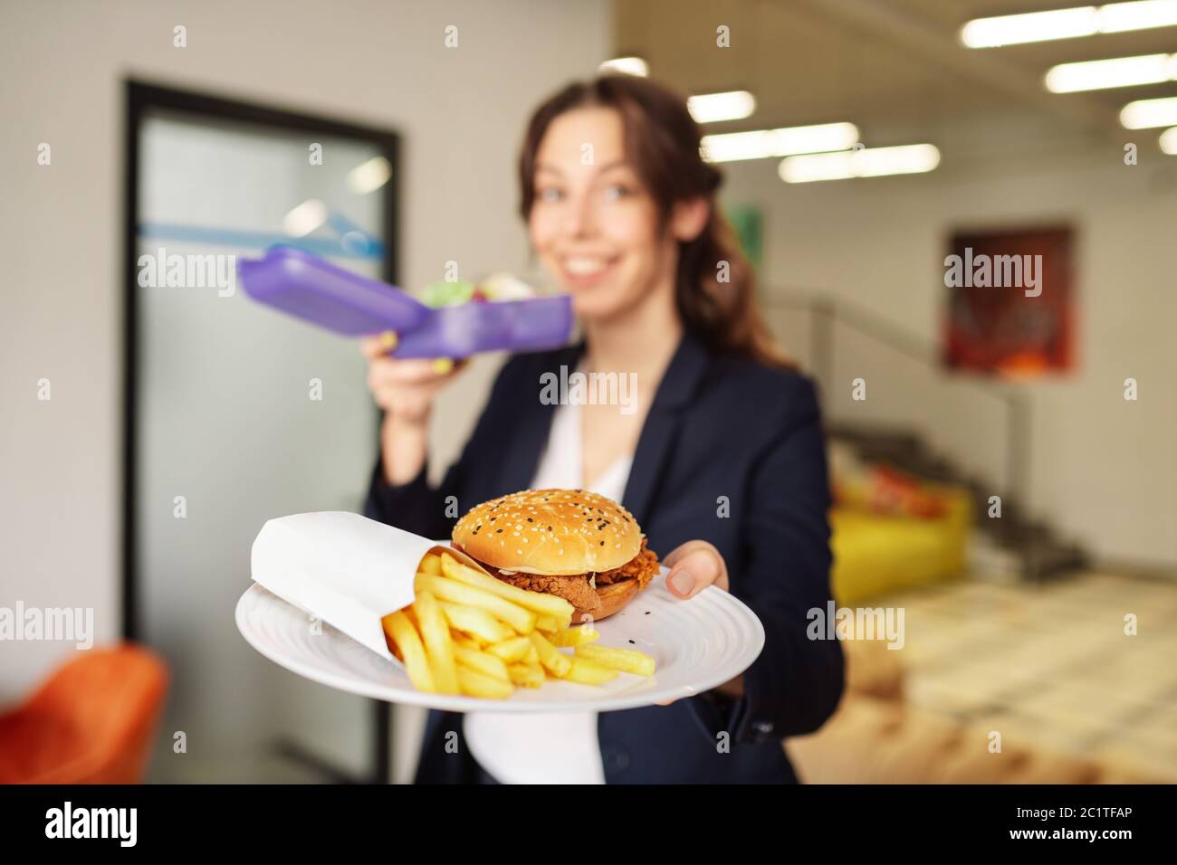 Glückliches Mädchen hält einen Teller mit Burger und Pommes Stockfoto