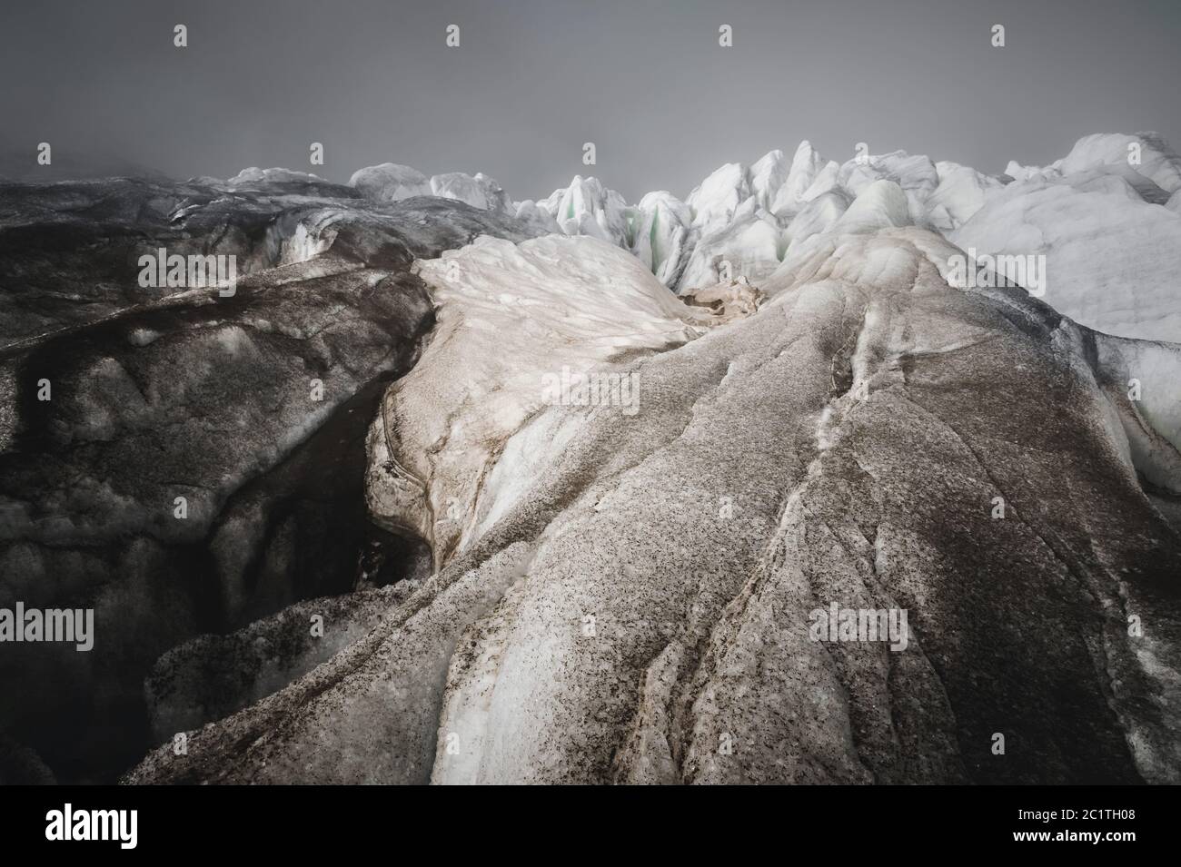 Nahaufnahme Crack ist ein tiefblauer Riss, der im Eisschild und im schwarzen Schlamm auf dem Gletscher gefunden wurde. Weitwinkel und dramatischer Himmel Stockfoto