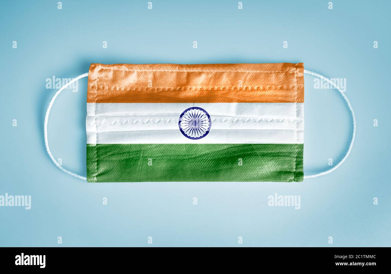 Covid-19 Coronavirus Schutzkonzept: Medizinische Einweg-Gesichtsmaske mit Indien-Flagge auf blauem Hintergrund. Stockfoto