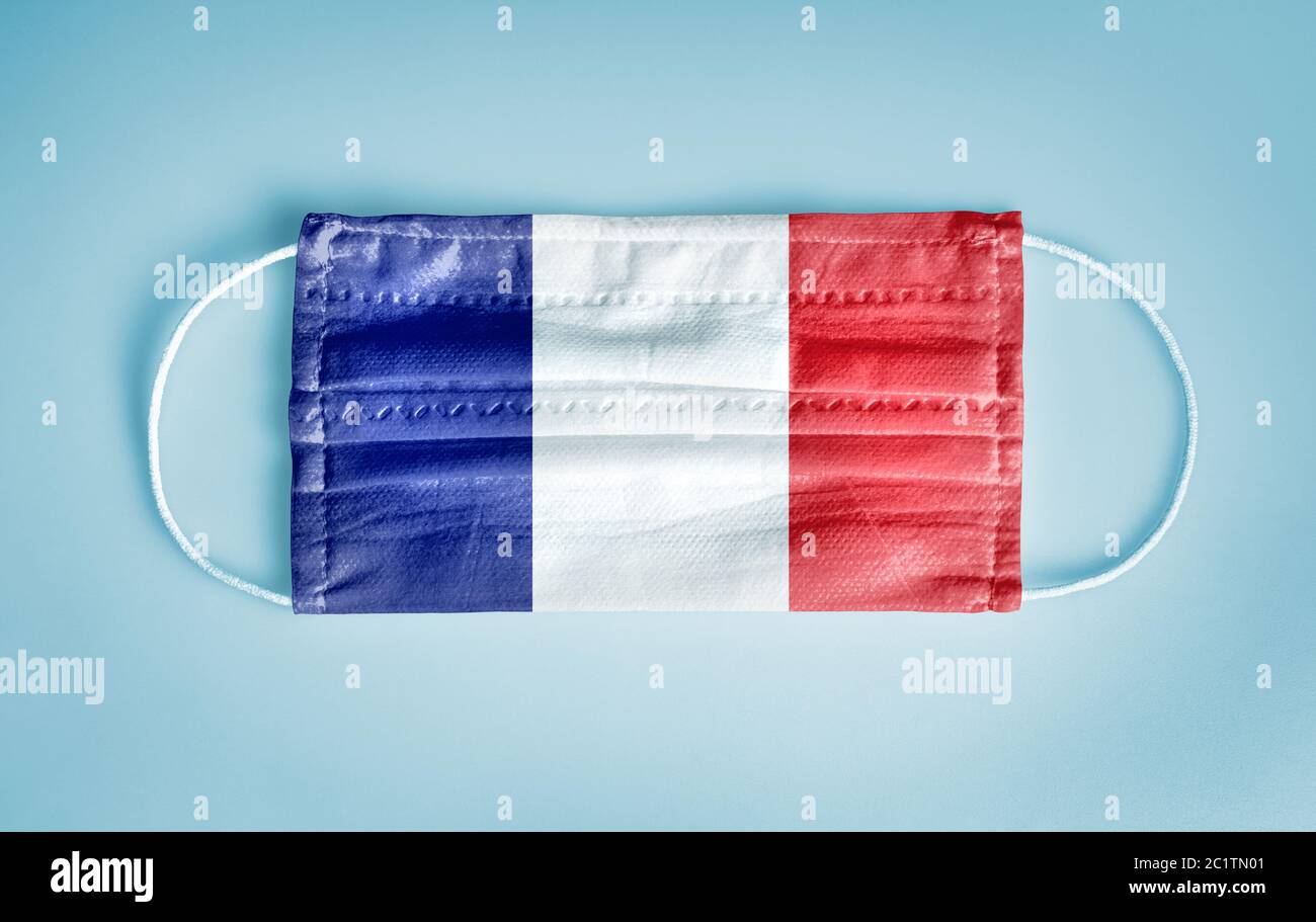 Covid-19 Coronavirus Schutzkonzept: Medizinische Einweg-Gesichtsmaske mit Frankreich Flagge auf blauem Hintergrund. WER empfiehlt die Verwendung von Maske für preventio Stockfoto