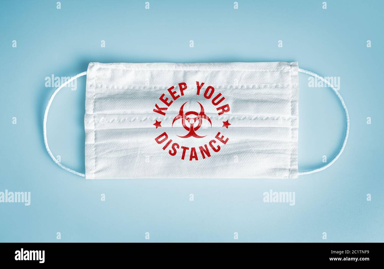 Covid-19 Coronavirus Schutz und soziale Distanzierung Konzept: Medizinische Einweg-Gesichtsmaske mit halten Sie Ihre Distanz Nachricht und Symbol auf blauem Rückengro Stockfoto