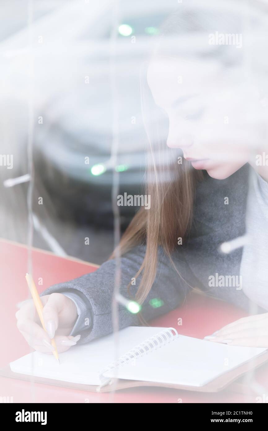 Porträt eines attraktiven jungen Journalistin Mädchen mit Stift und Notizblock im Café hinter der Vitrine. Kontrastfreie Sicht durch Wind Stockfoto