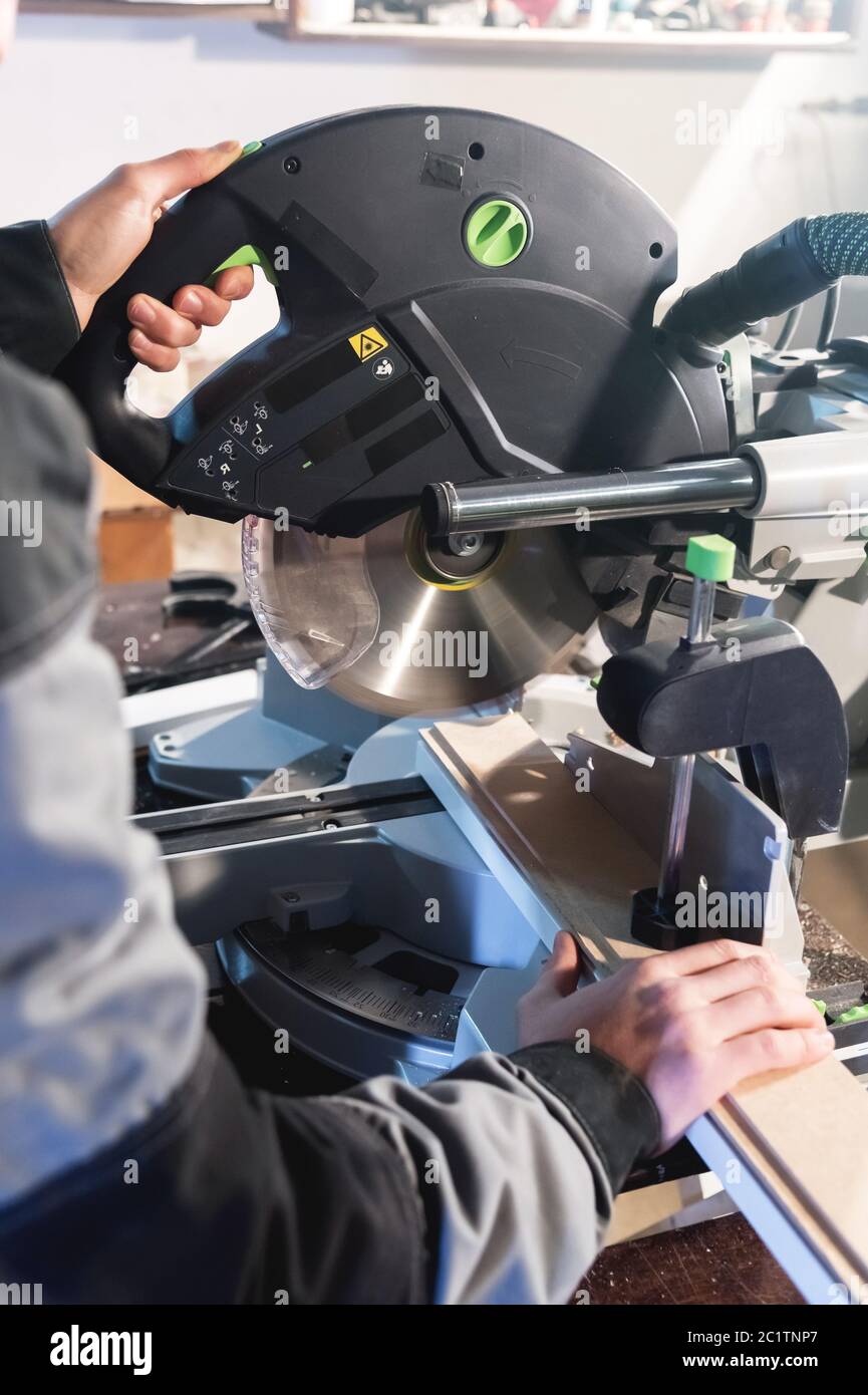 Nahaufnahme der Hände nach dem Beruf ein Zimmermann schneidet Holzbretter mit einer Kreissäge auf einem Arbeitstisch in einer Werkstatt. Professio Stockfoto