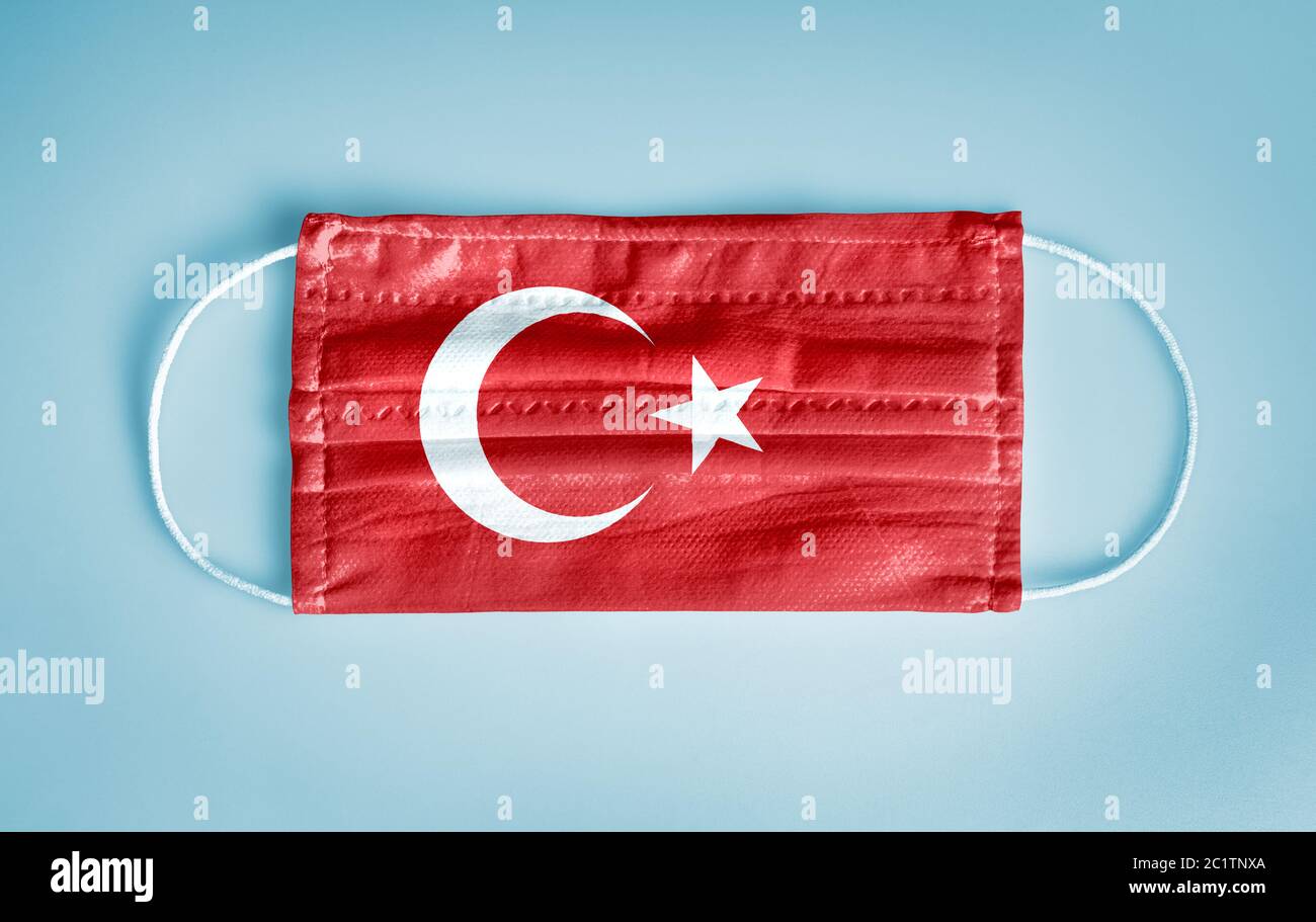 Covid-19 Coronavirus Schutzkonzept: Medizinische Einweg-Gesichtsmaske mit Türkei-Flagge auf blauem Hintergrund. Konzept der sozialen Distanzierung. Stockfoto