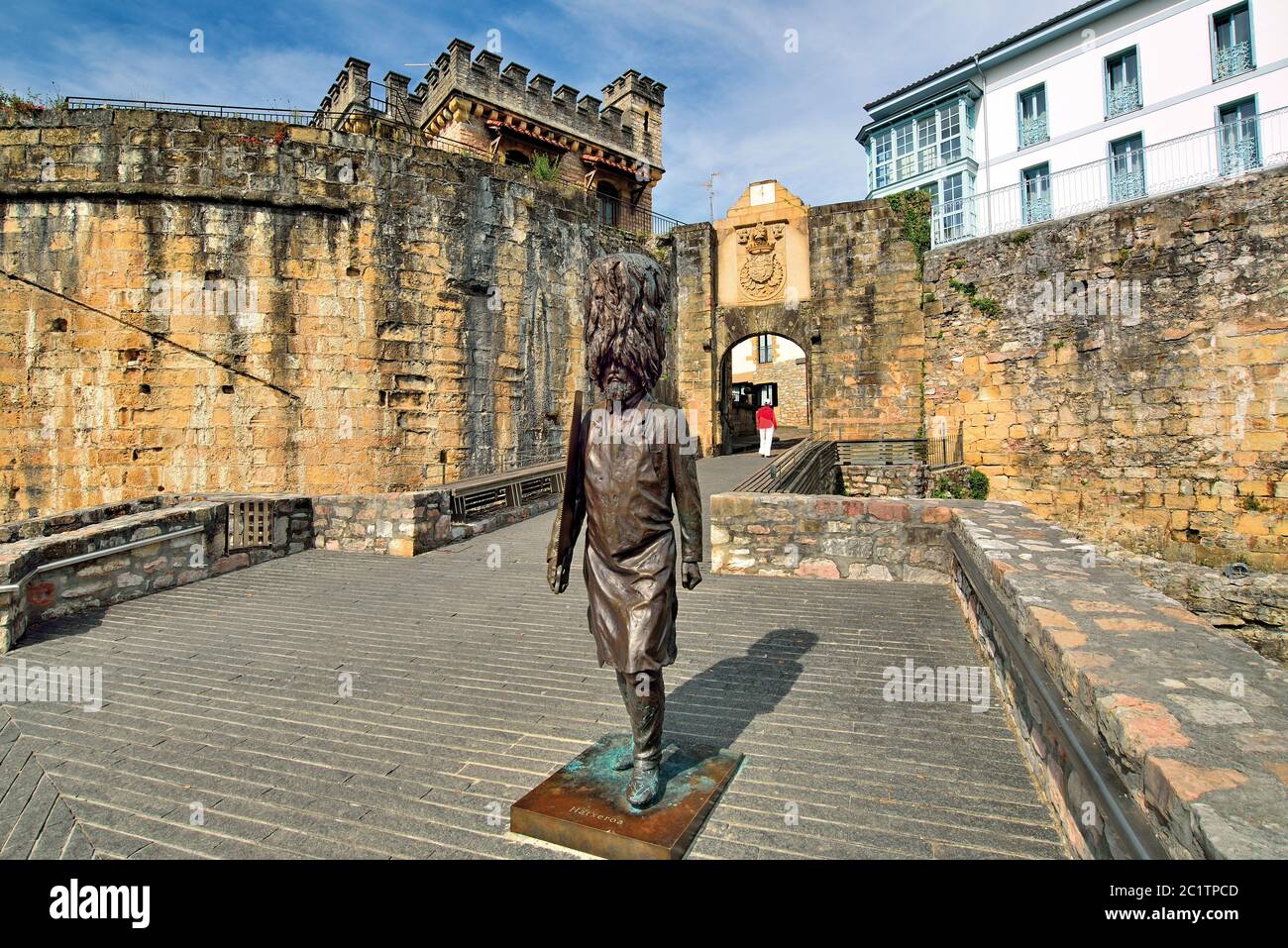 Bronzestatue und Frau mit rotem Pullover über mittelalterliches Portal (Hondarribia, Basaue Country) Stockfoto