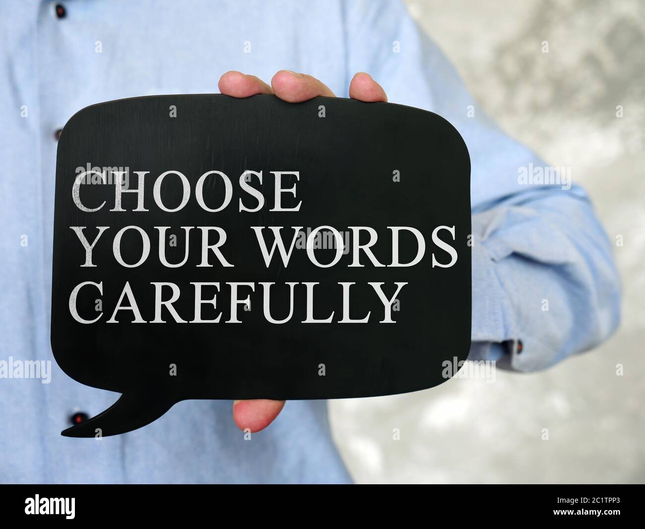 Hand hält eine schwarze Tafel mit der Aufschrift Wählen Sie Ihre Worte sorgfältig. Stockfoto