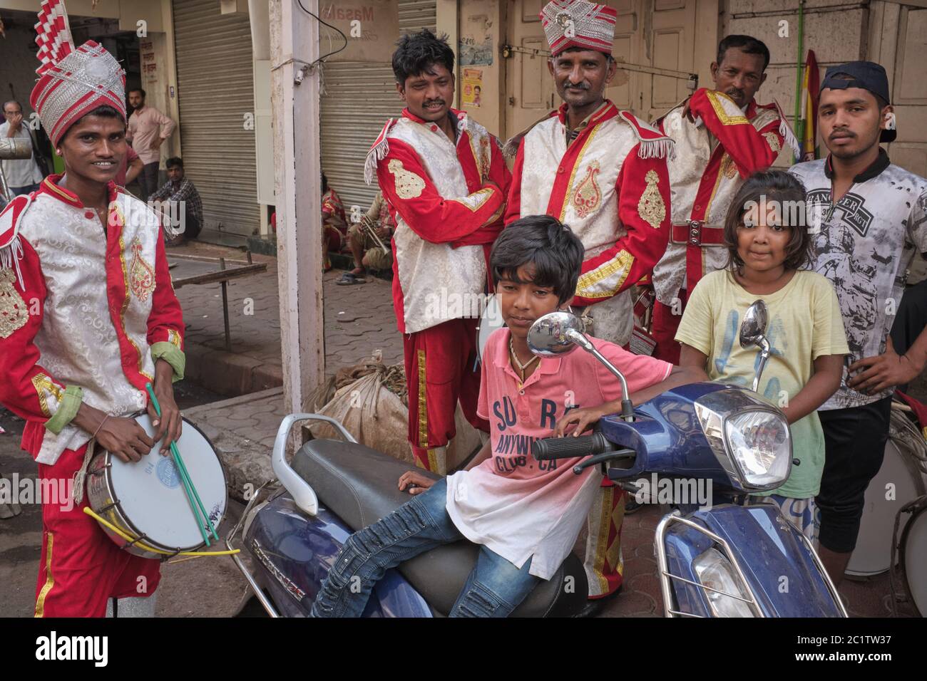 Uniformierte indische Hochzeitsband und Festival-Musiker während einer Pause mit Einheimischen vermischt; Mumbai, Indien Stockfoto