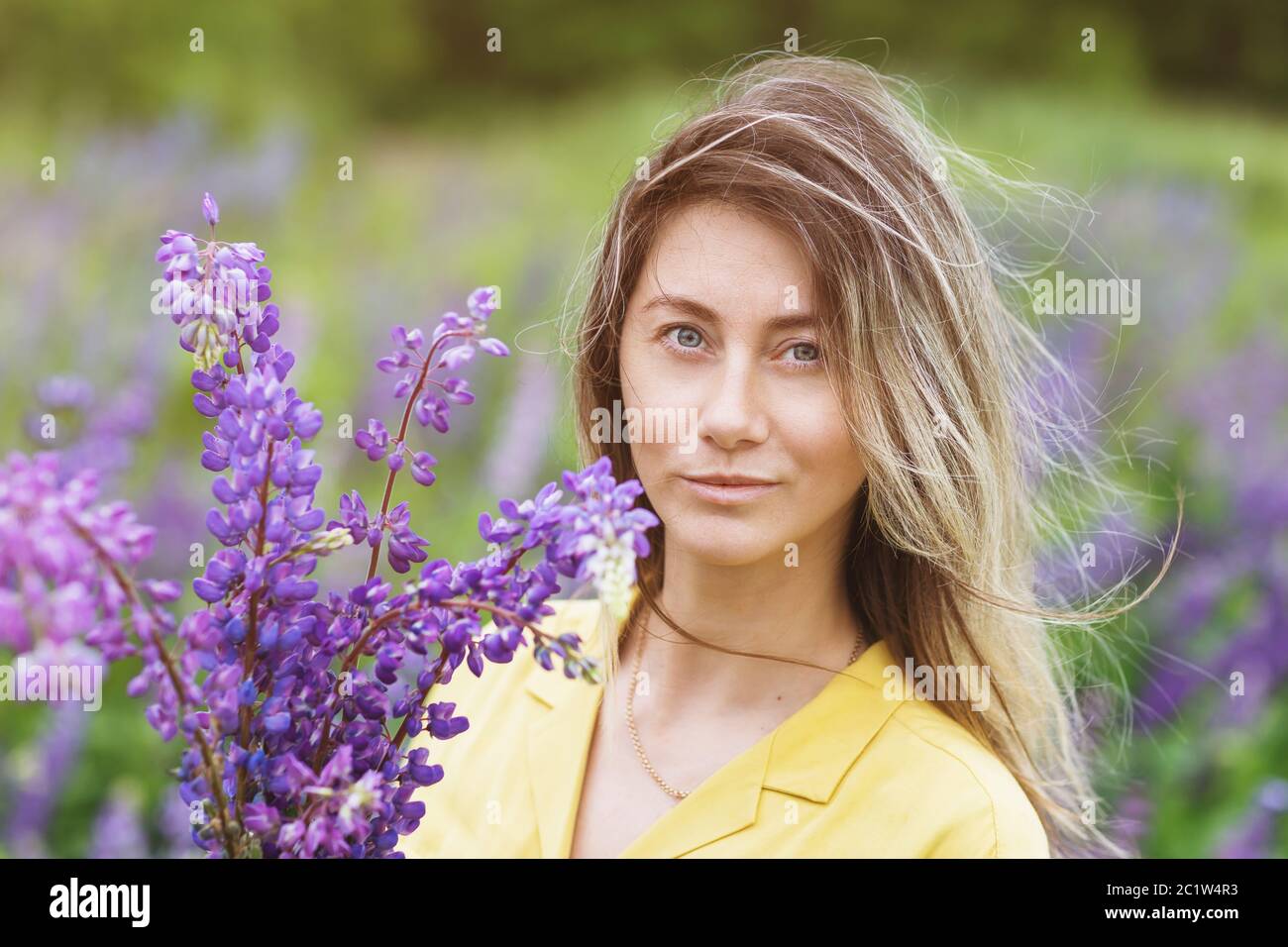 Portrait eines Mädchens mit Lupinen an einem Sommertag, Nahaufnahme Stockfoto