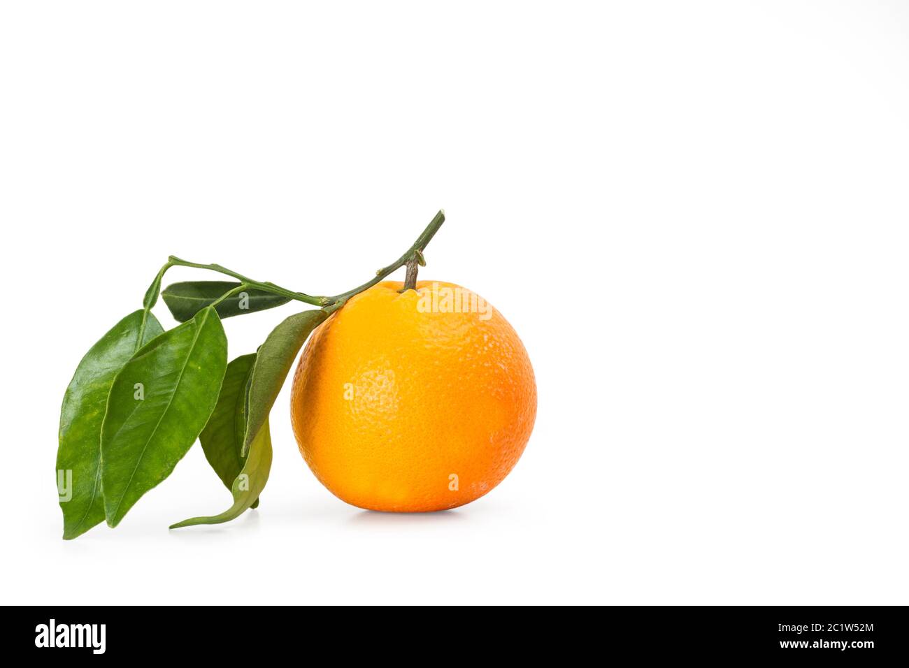 Eine Orange mit grünen Blättern auf gelbem Hintergrund Stockfoto