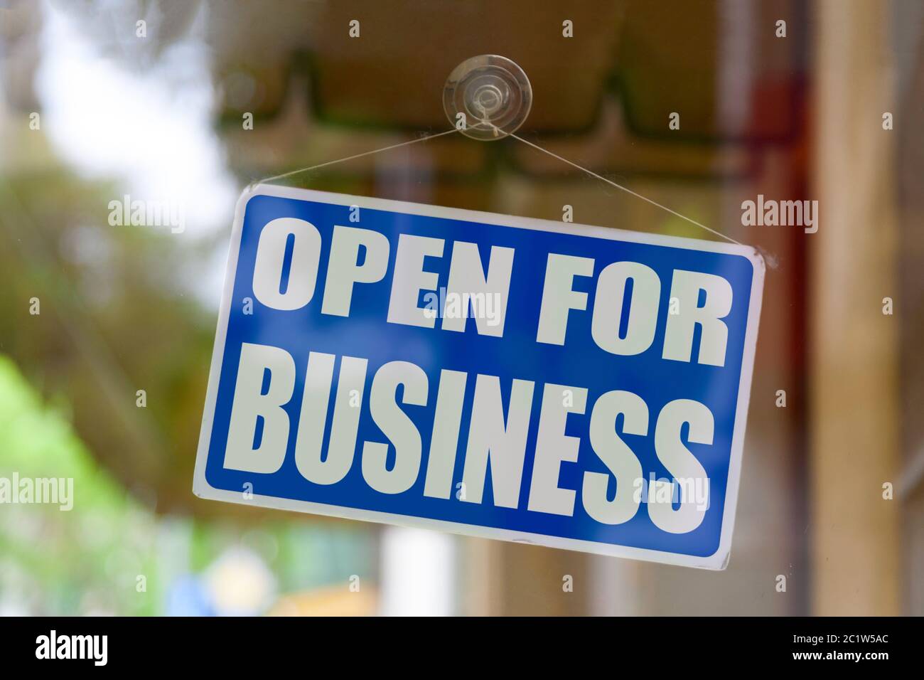 Nahaufnahme eines blauen geöffneten Schildes im Schaufenster eines Geschäfts mit der Meldung „für Unternehmen geöffnet“. Stockfoto