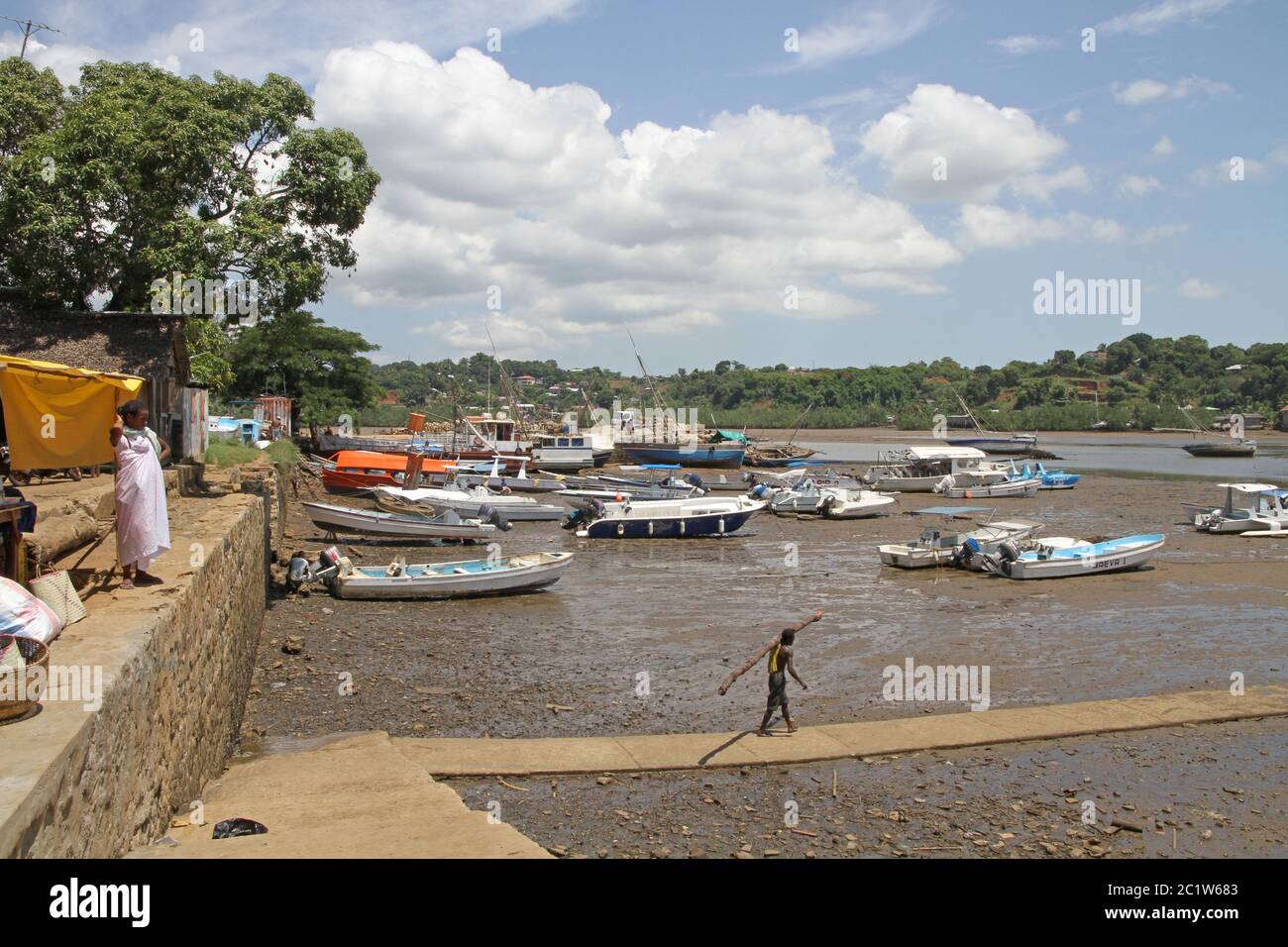 Boote und Mann mit Holzbesen in Andoany Harbour oder Hell-Ville Harbour, Nosy Be, Madagaskar. Stockfoto