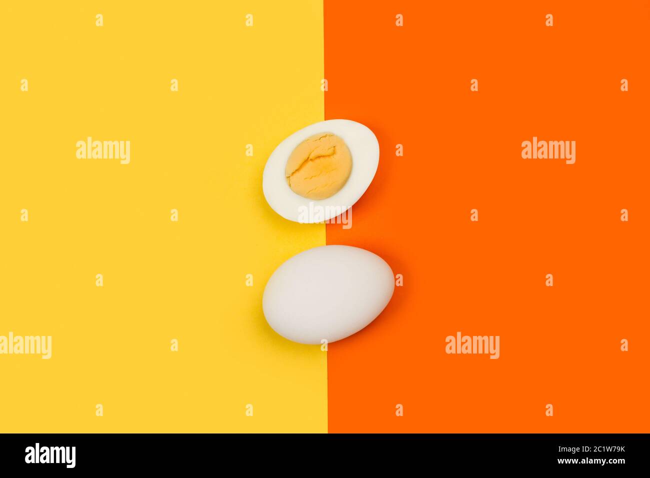Halbierte gekochte Eier und ein Ei auf gelbem und orangefarbenem Hintergrund Stockfoto