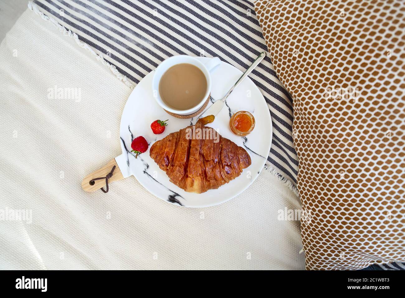 Frühstück mit Croissant, Kaffee, Erdbeere und Marmelade auf dem Teller Tablett im Bett Stockfoto