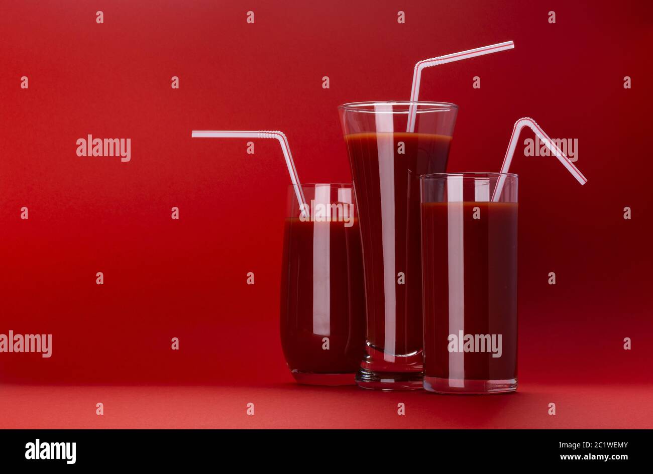 Glas Tomatensaft isoliert auf rotem Hintergrund mit Kopierraum Stockfoto