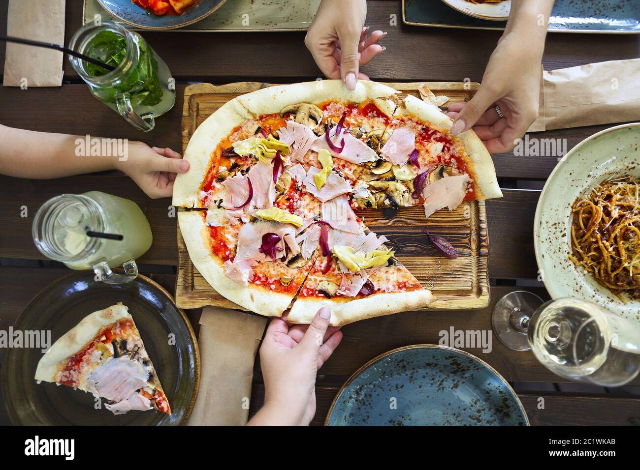 Konzept der freundlichen Familie Abendessen Party Vorbereitung. Horizontal, Abendessen mit Pizza, Pasta, Weißwein und Limonade Stockfoto