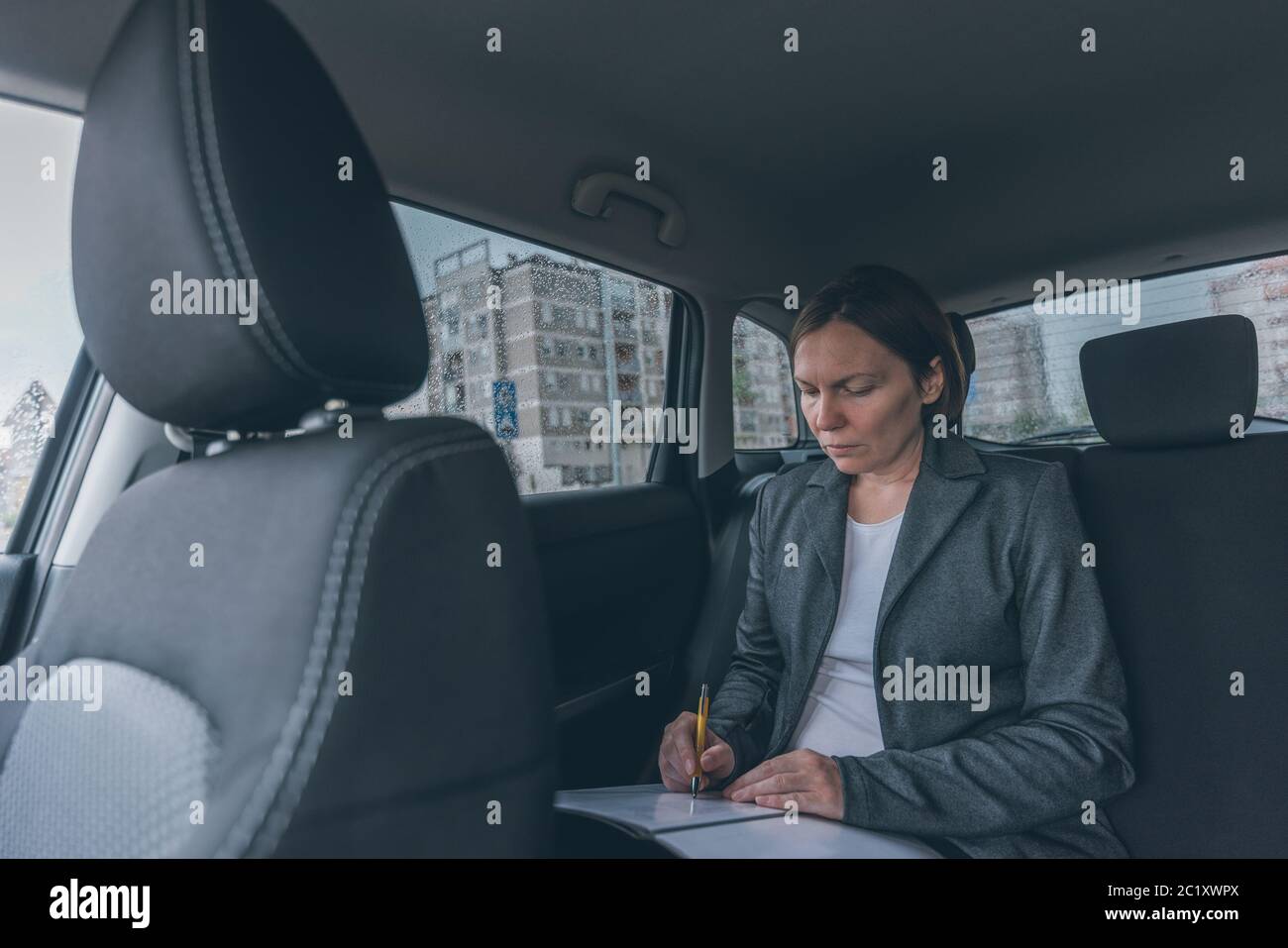 Geschäftsfrau, die Papiere auf dem Rücksitz, Erwachsene kaukasischen weibliche Unternehmer executive Analyse von Ergebnissen während der Fahrt Stockfoto