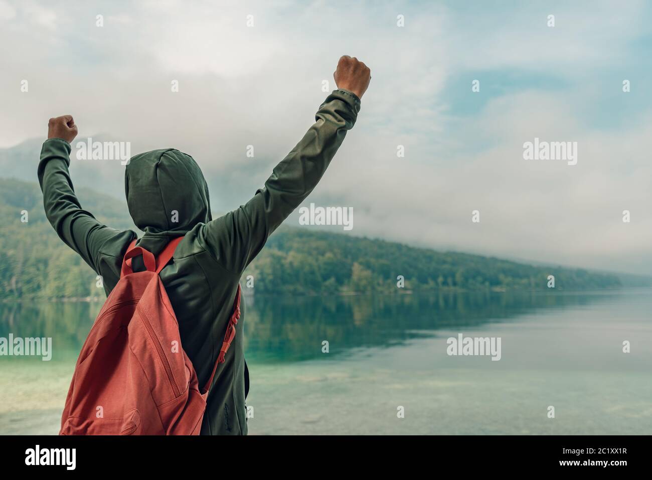 Rückansicht der weiblichen Wanderer Arme zum See angehoben genießen die Aussicht auf den See in nebligen Sommermorgen Stockfoto