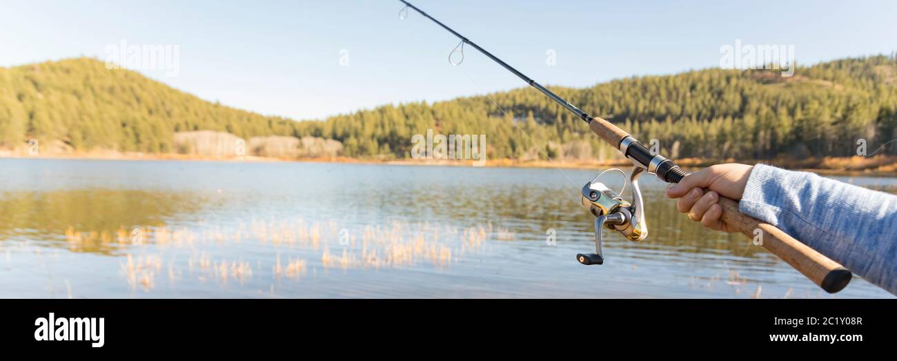 Angelrute in der Hand des Angler auf einem kleinen ruhigen See Stockfoto