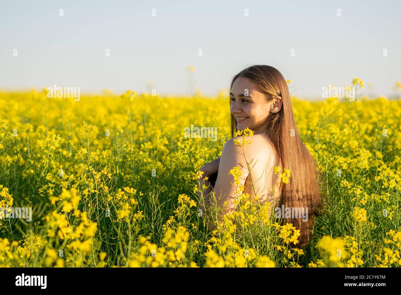 Schönes Mädchen in einem Rapsfeld, mit einer offenen Schulter. Stockfoto