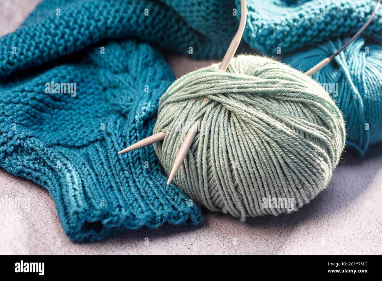 Kugeln aus farbigem Garn mit Stricknadeln aus nächster Nähe Stockfoto