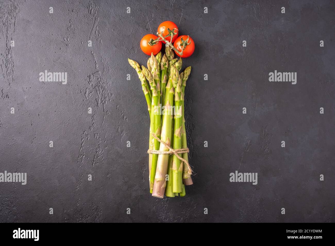 Konzept eines Strauß Spargel und Kirschtomaten in Form einer Blume auf dunklem Hintergrund. Draufsicht mit Kopierbereich Stockfoto