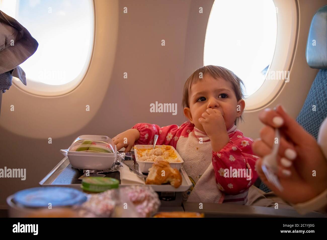 Niedliche Kleinkind Flugzeug Passagier isst spezielle Baby an Bord Mahlzeit Umfliegen Flug Stockfoto
