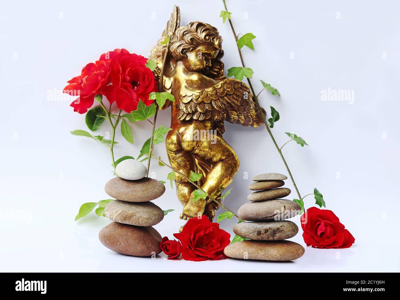 Ein goldener Engel mit roten Rosen, Efeu und Steintürmen Stockfoto