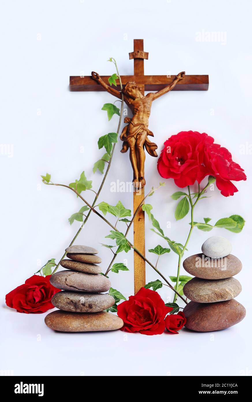 Ein christliches Kreuz mit roten Rosen, Efeu und Steintürmen Stockfoto