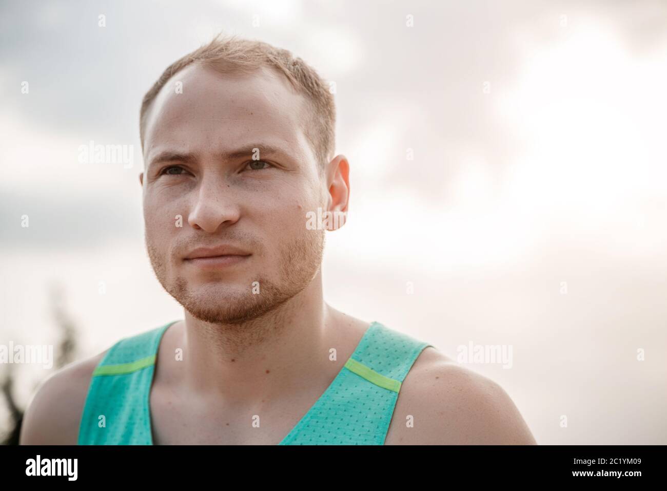 Portrait der kaukasischen Kerl in einem Azure T-Shirt und schwarze Shorts über unebenes Gelände laufen. Ausbildung bei Sonnenuntergang Stockfoto