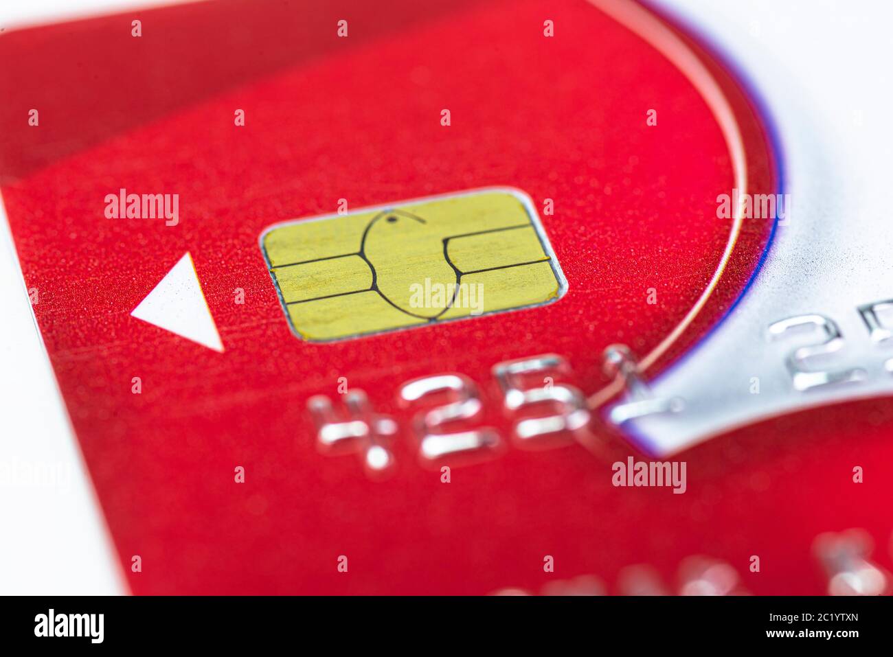 Makroaufnahme eines roten Kreditkartenchips mit silbernem Schriftzug und weißem Pfeil. Stockfoto