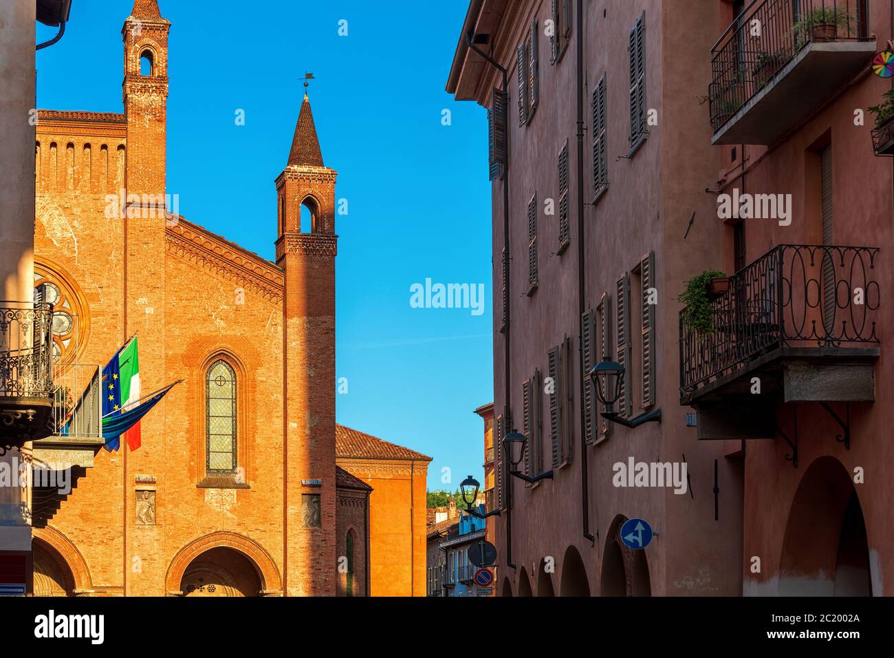 Blick auf die Kathedrale von San Lorenzo unter alten Häusern unter blauem Himmel in Alba, Piemont, Norditalien. Stockfoto