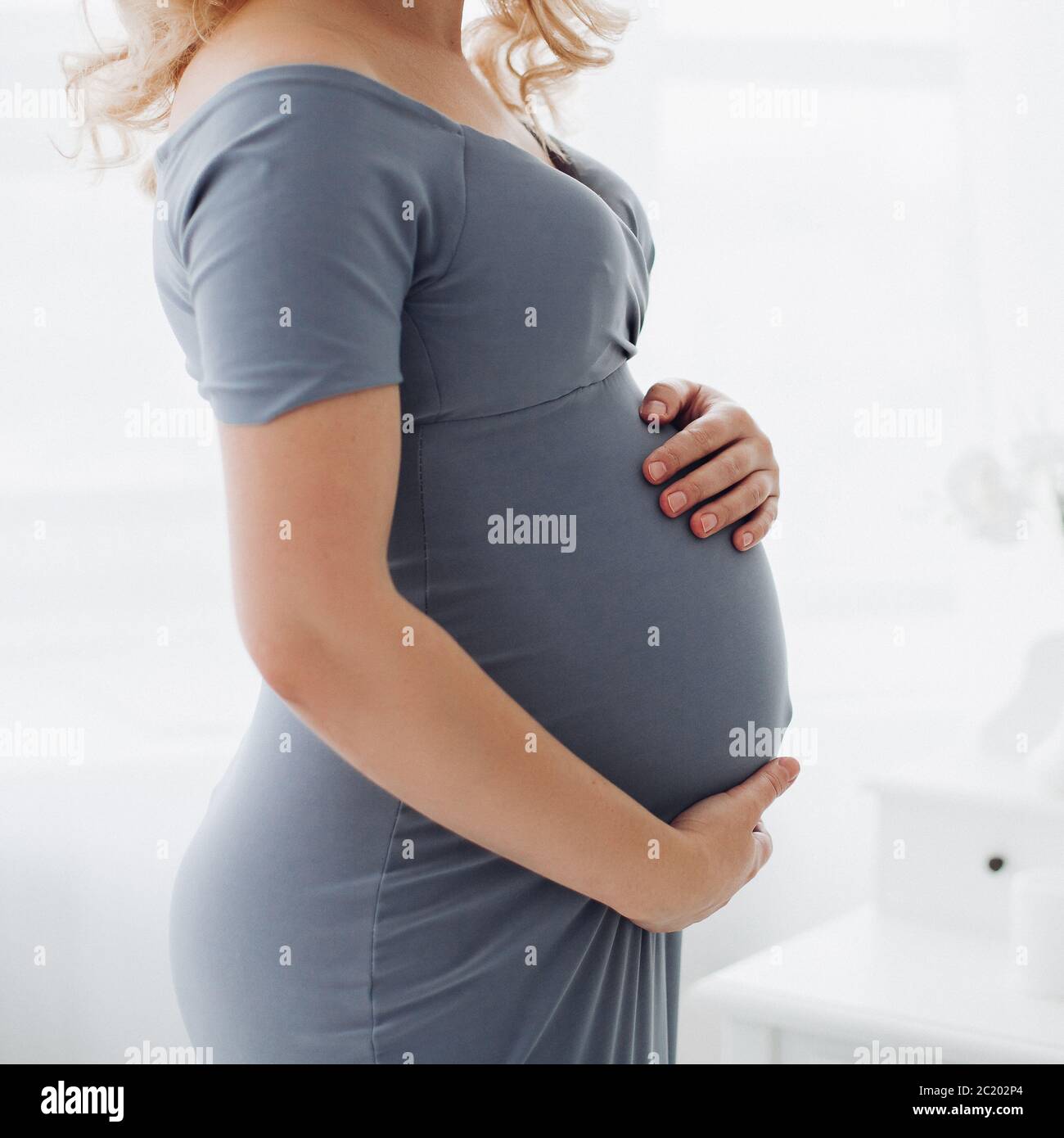 Schöne schwangere Frau, Hände auf Bauch am Herzen. Stockfoto