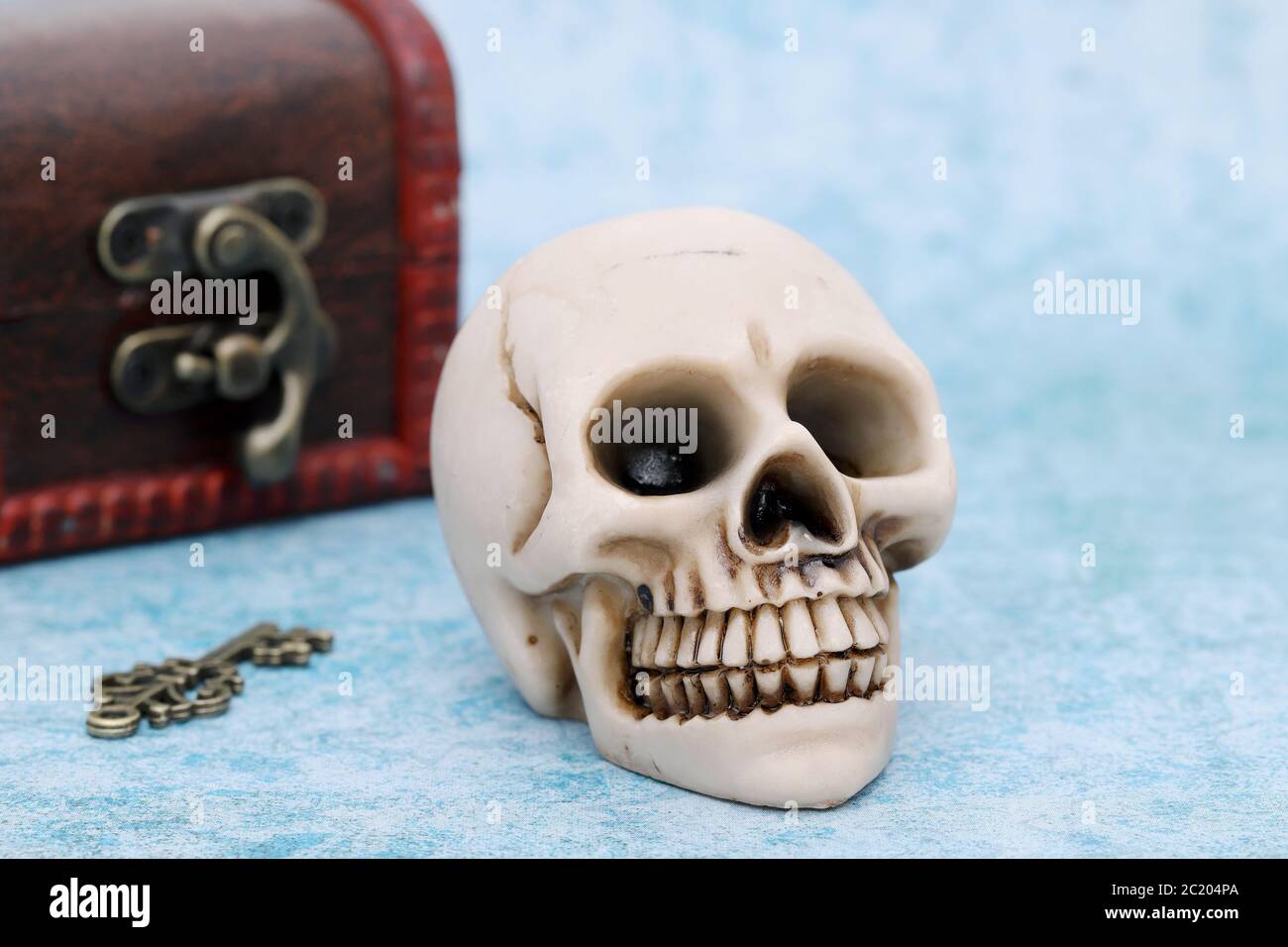 Menschlicher Schädel mit alten Schatztruhe auf blauem Hintergrund Stockfoto