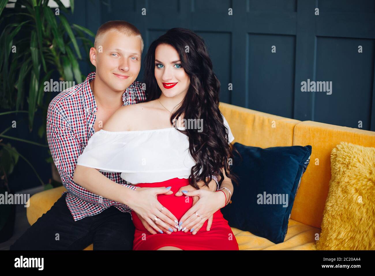 Stilvolle Paare sitzen auf gelbes Sofa und Blick auf Kamera. Stockfoto