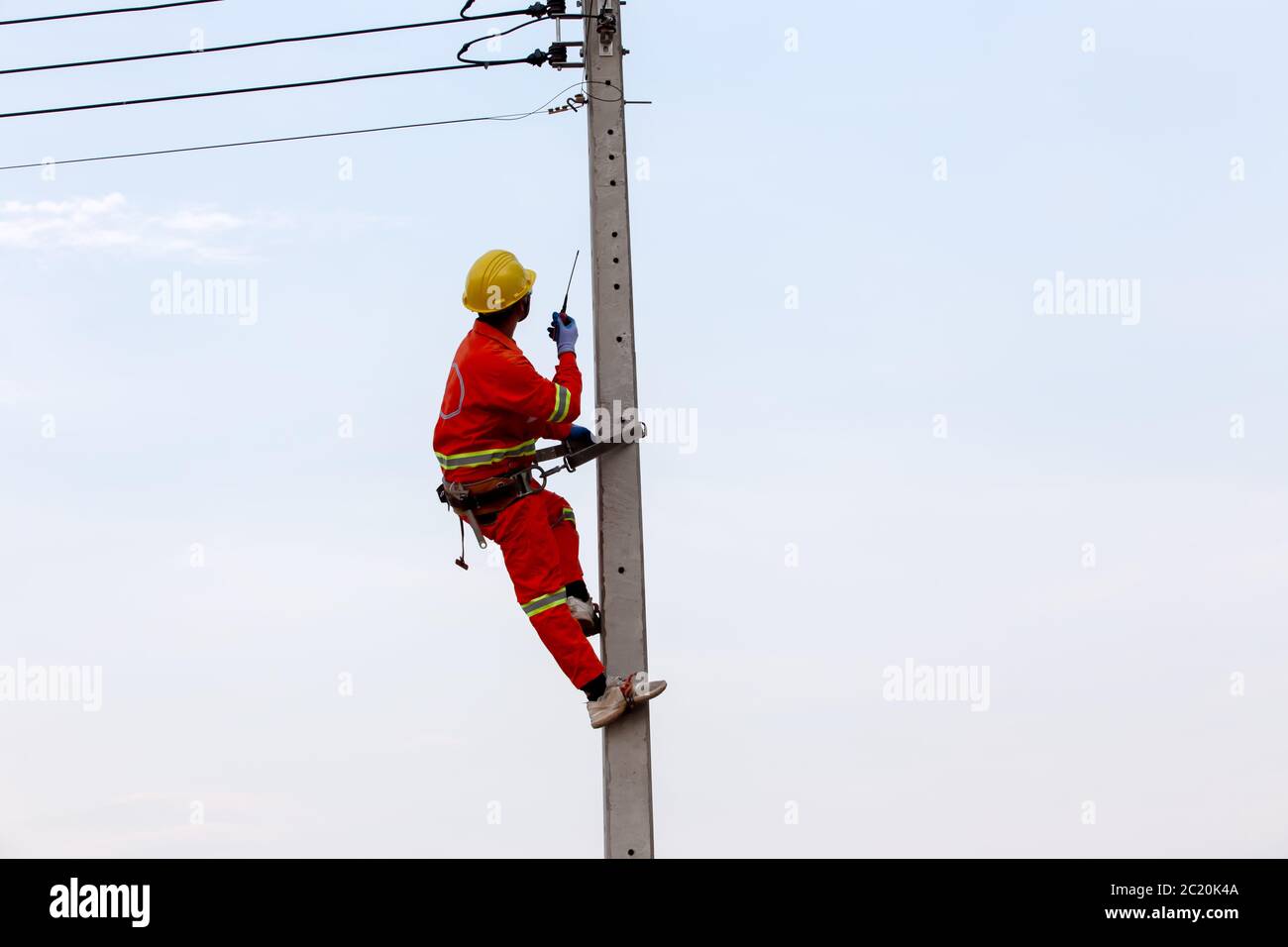 Uniformierte Elektriker arbeiten an Hochhausstrommohlen zusammen mit Sicherheitsausrüstung und Funkkommunikation. Stockfoto