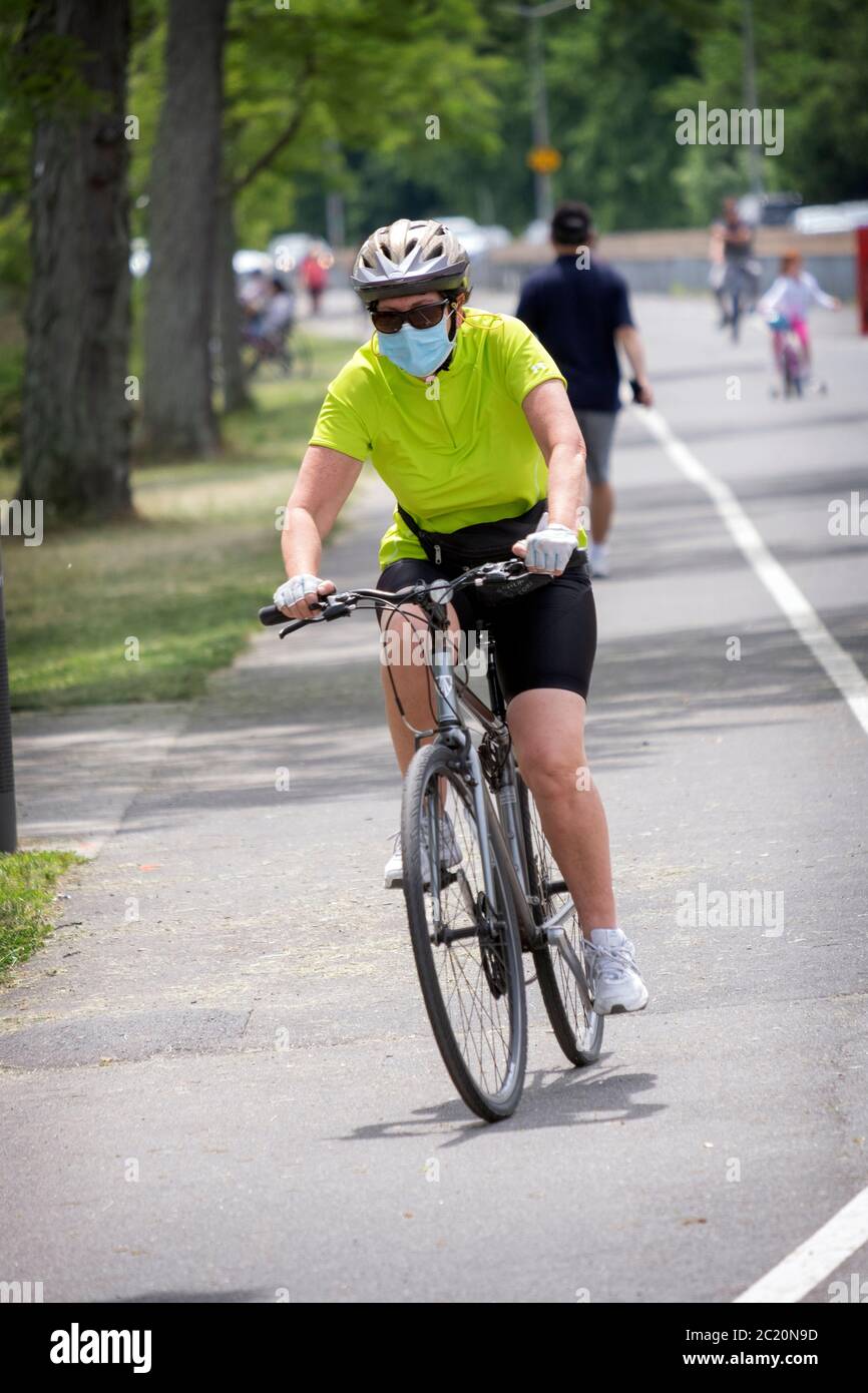 Ein Biker fährt auf einem Pfad nahe dem Cross Island Parkway mit Maske und Helm. In Bayside, Queens, NYC. Stockfoto