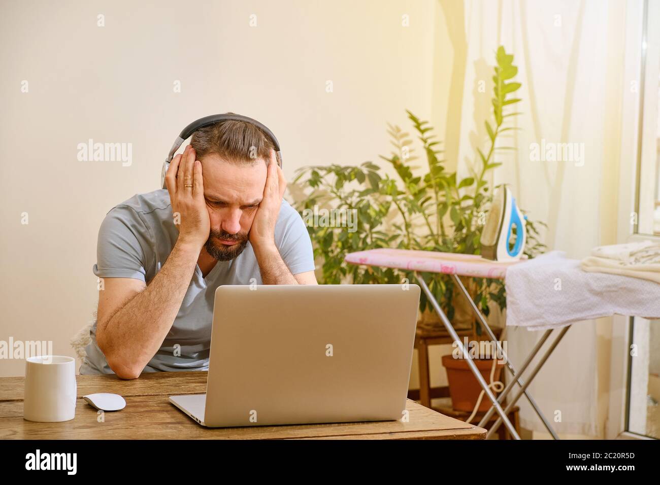 Ein trauriger Kaukasusmann in Verzweiflung schaut auf einen Computermonitor. Telearbeit und Finanzkrise Konzept. Stockfoto