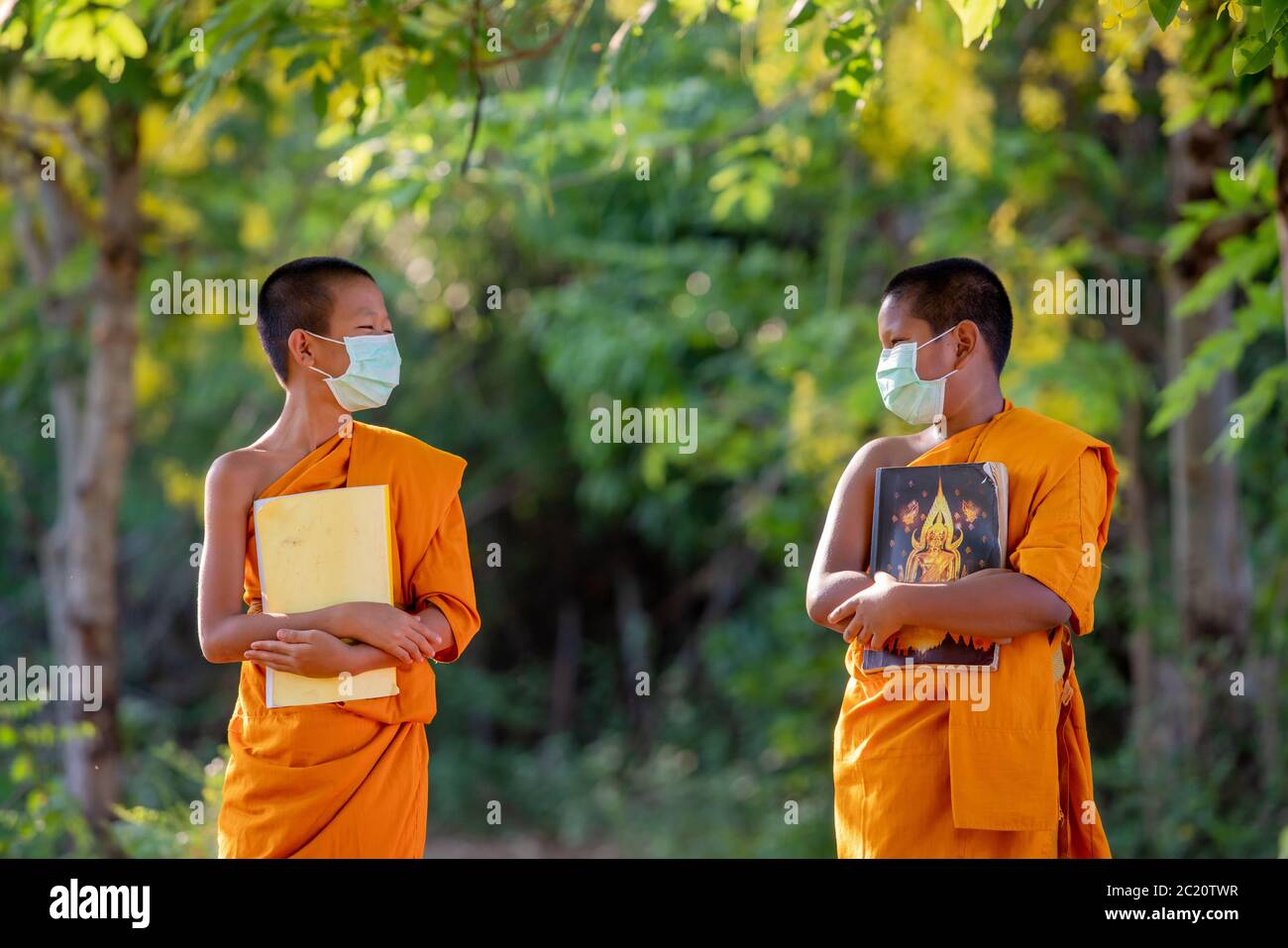 Novize Mönch trägt Maske soziale Distanzierung und genießen mit Freund neue normale von Coronavirus oder Covid-19 betroffen Stockfoto