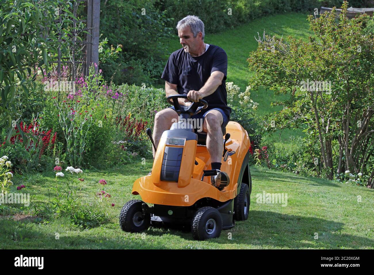 Ein Mann mäht den Rasen mit einem Aufsitzmäher. Rasenmähen im Sommer Stockfoto