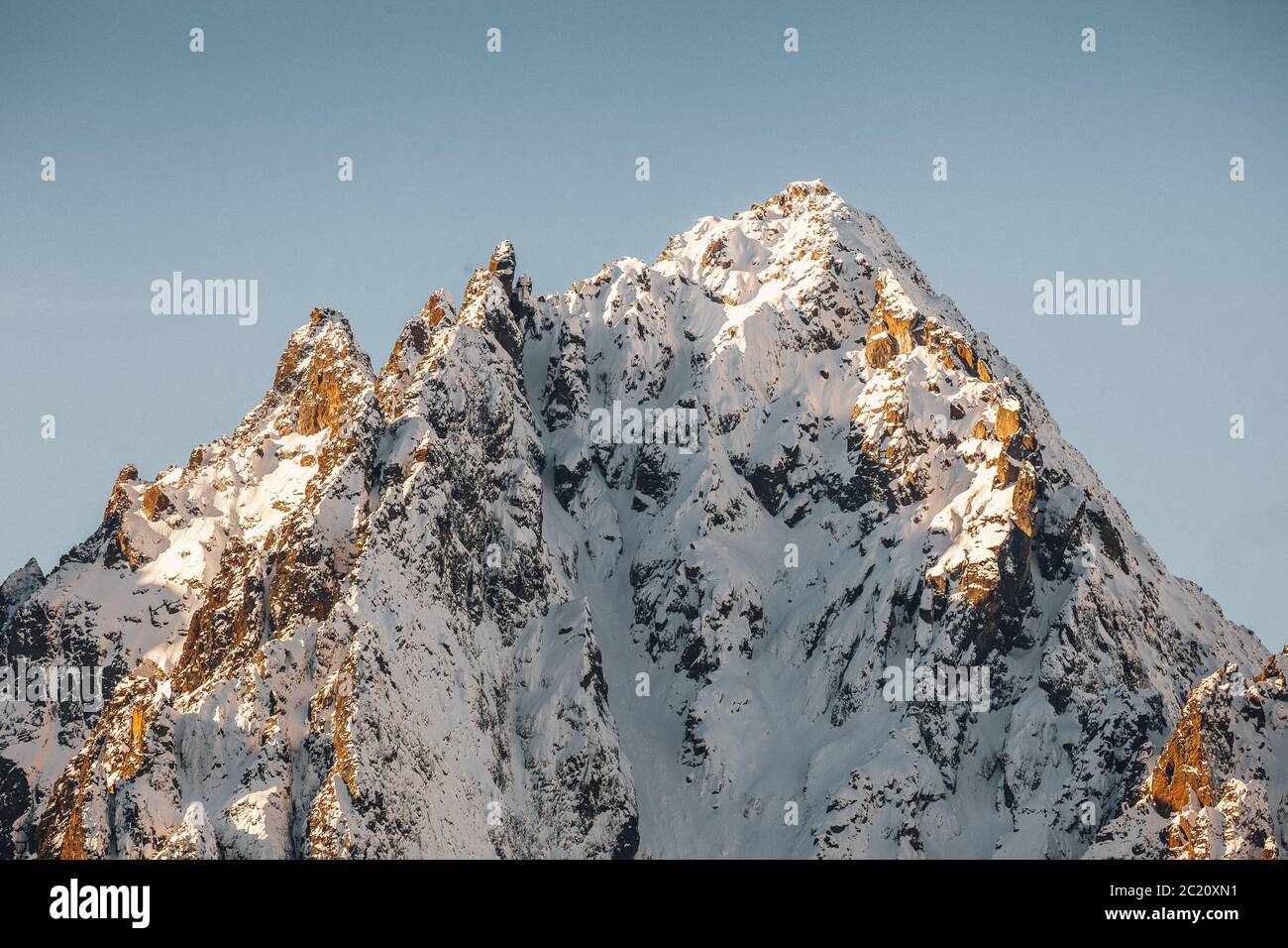 Schneebedeckte Bergspitze, Nahaufnahme mit goldenem Licht und blauem Himmel, französische Alpen. Stockfoto