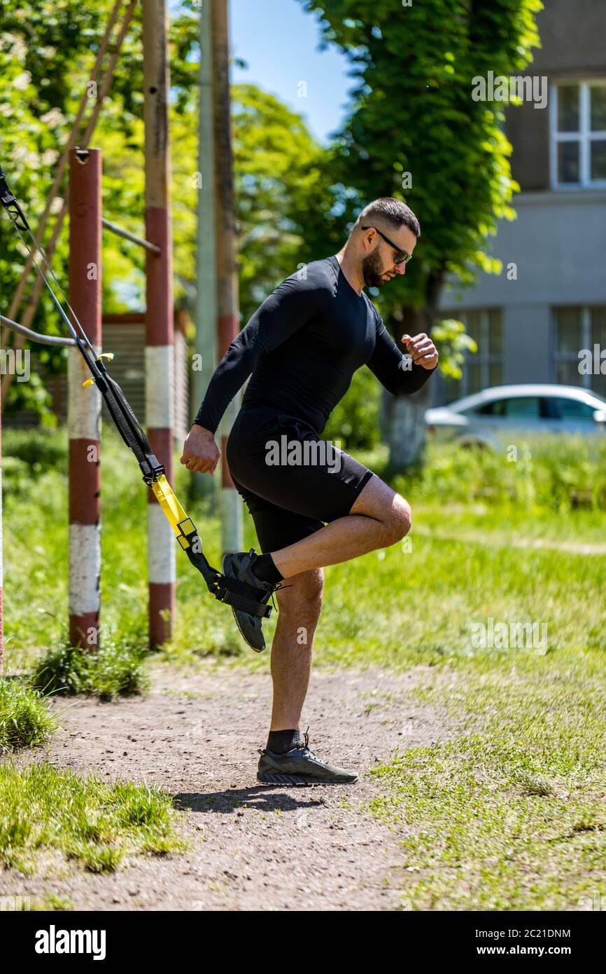 Mann trainiert bauchmuskeln mit Federung Fitness-Gurte im Fitnessstudio. Magen Bauchmuskeln Training gesunde Lebensweise Sport. Stockfoto