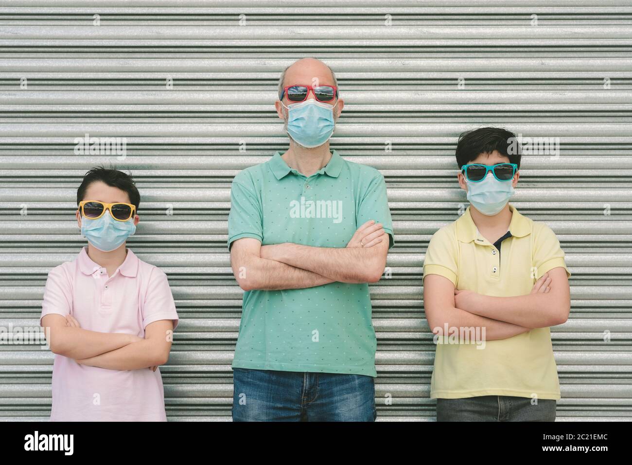 Vater mit seinen Söhnen trägt medizinische Maske und Sonnenbrille im Freien Stockfoto