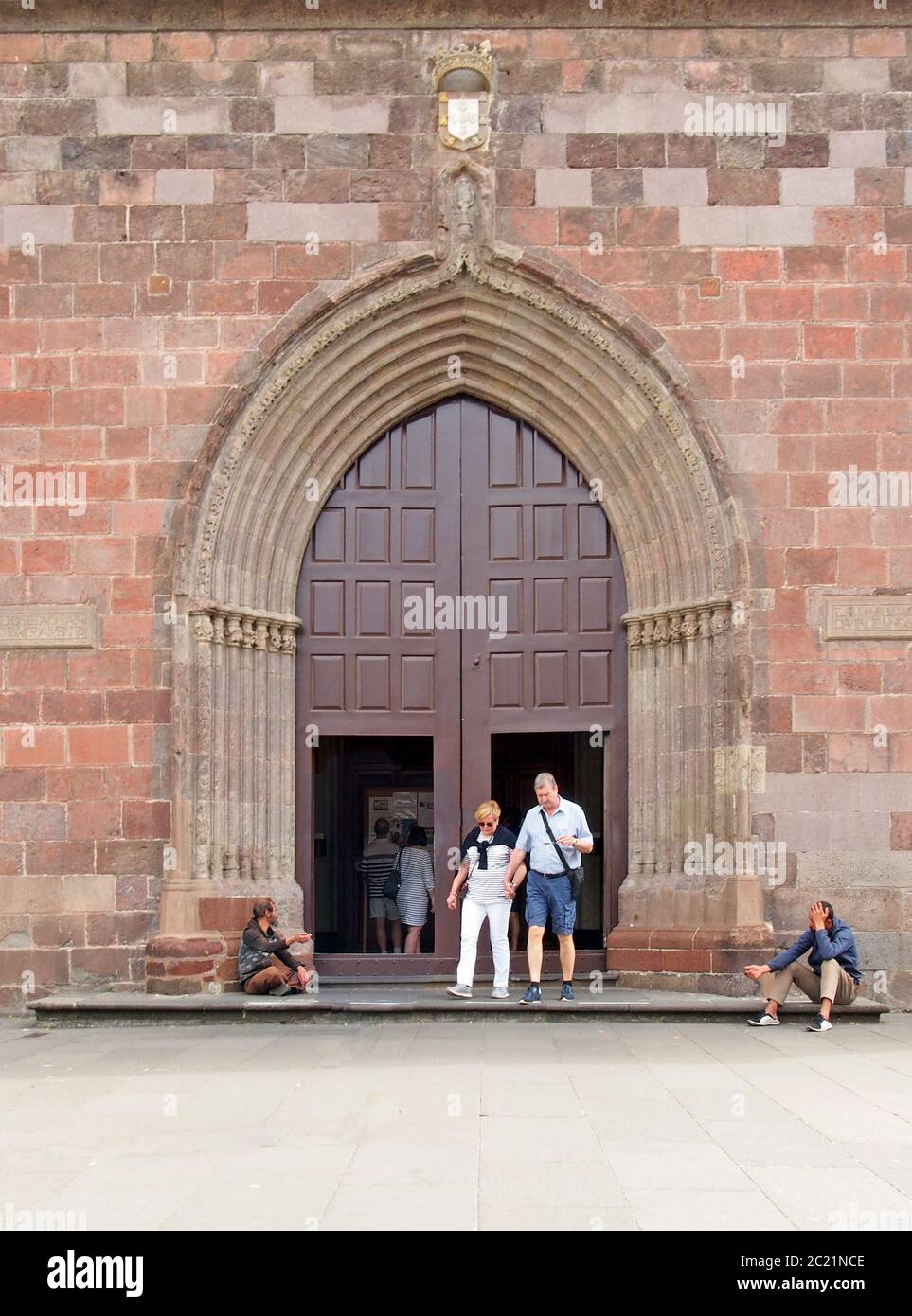 Menschen vor der Tür der kathedrale von funchal auf madeira mit Bettlern, die draußen auf den Stufen sitzen Stockfoto