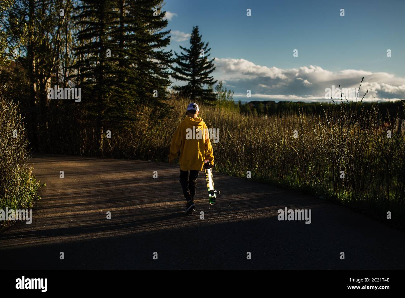 Teen junge zu Fuß in der Dämmerung mit Skateboard Stockfoto