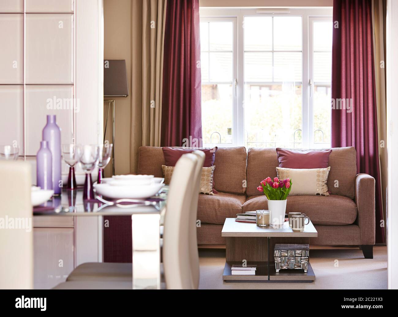 Aufnahme von moderner Wohnzimmereinrichtung mit Esstisch vorne und Sofa im Hintergrund Stockfoto