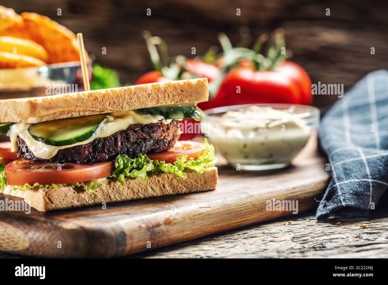Hackbohnen vegetarischer Toast mit Salat, Tomaten und Gurken, umgeben von rustikalem Holz Stockfoto
